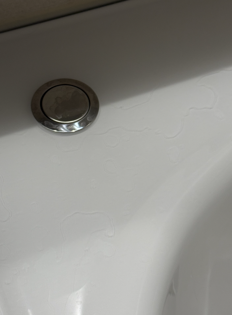 白いバスタブのクリア層に付いた水垢