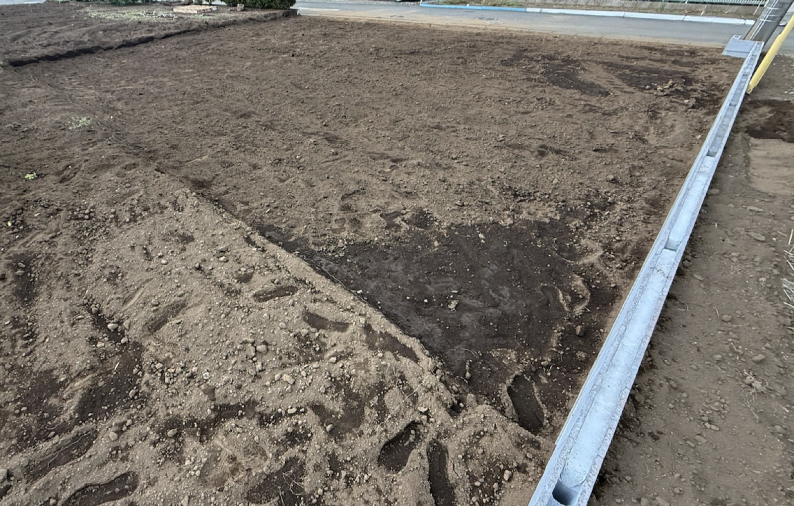 一次外構が完成した我が家の敷地。家が建つ部分は掘り込まれ、隣地との境界にブロック塀が並び、道路とはフラットにつながっている