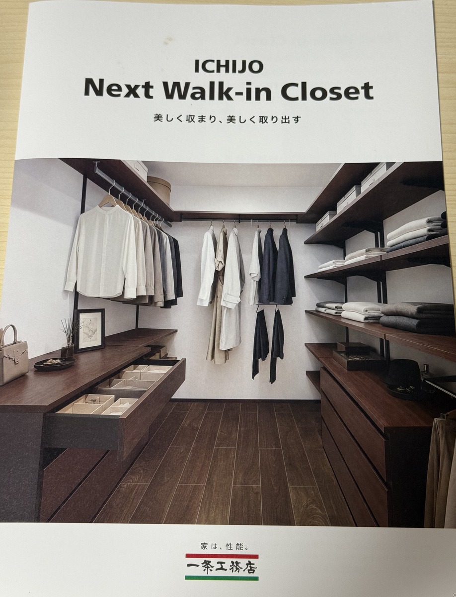 一条工務店の公式パンフレット「ICHIJO Next Walk-in Closet 〜美しく収まり、美しく取り出す〜」の表紙。濃い木目の棚とハンガーが並ぶウォークインクローゼットの完成イメージ写真